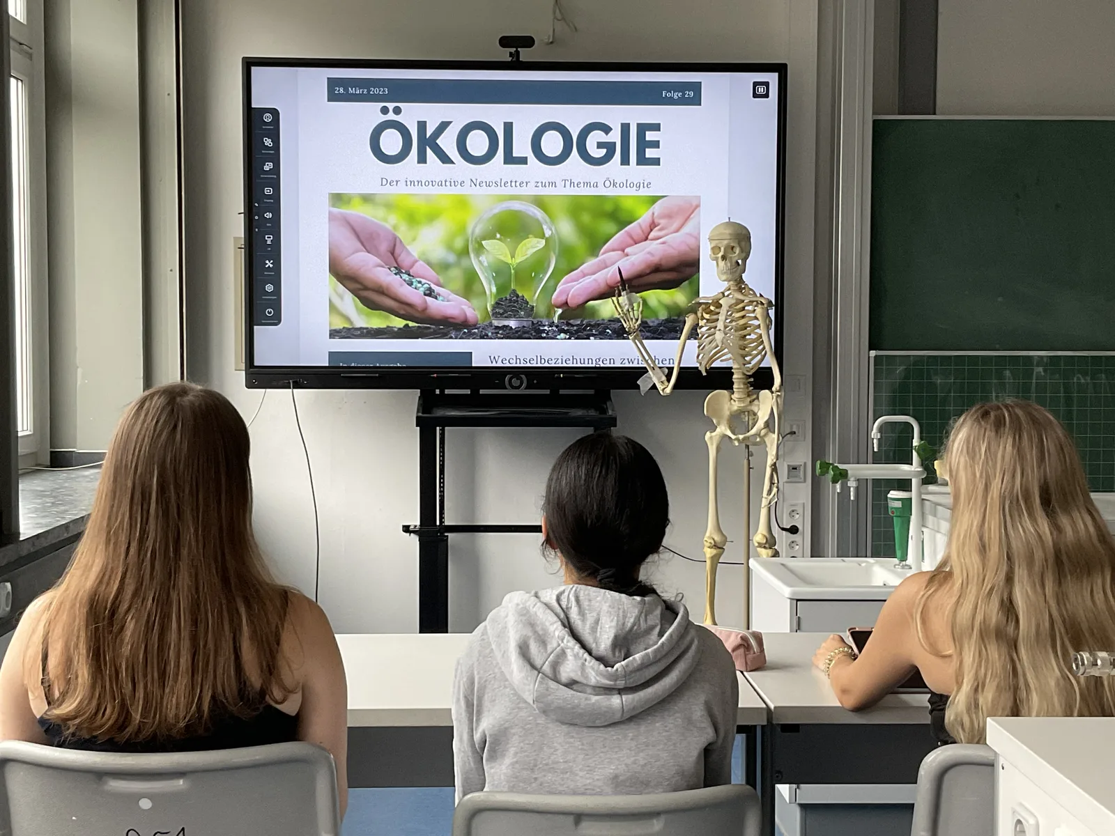 Schülerinnen vergleichen einen menschlichen Schädel mit einem Primatenschädel im Biologieunterricht